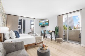 Ein modernes Hotelzimmer mit Bett, Schreibtisch, Fernseher und Balkon mit Blick auf die Stadt.