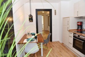 Une cuisine moderne dotée d’un plan de travail en bois, d’appareils électroménagers en acier inoxydable et d’un coin repas avec une table dressée pour deux personnes.