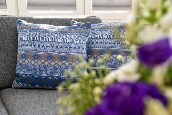 A grey sofa with patterned cushions and a window in the background.