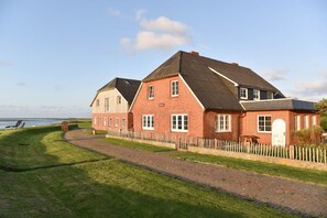 Une grande maison en briques avec une allée pavée et une clôture en bois.