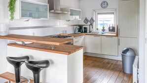 A modern kitchen with a wooden island, white cabinets, and two black bar stools. - Pet friendly home in Opperdoes (Opperdoes)
