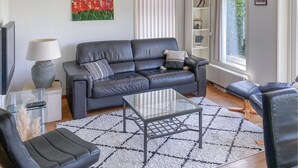 A modern living room with a grey leather sofa, a glass coffee table, and a patterned rug. - Pet friendly home in Opperdoes (Opperdoes)