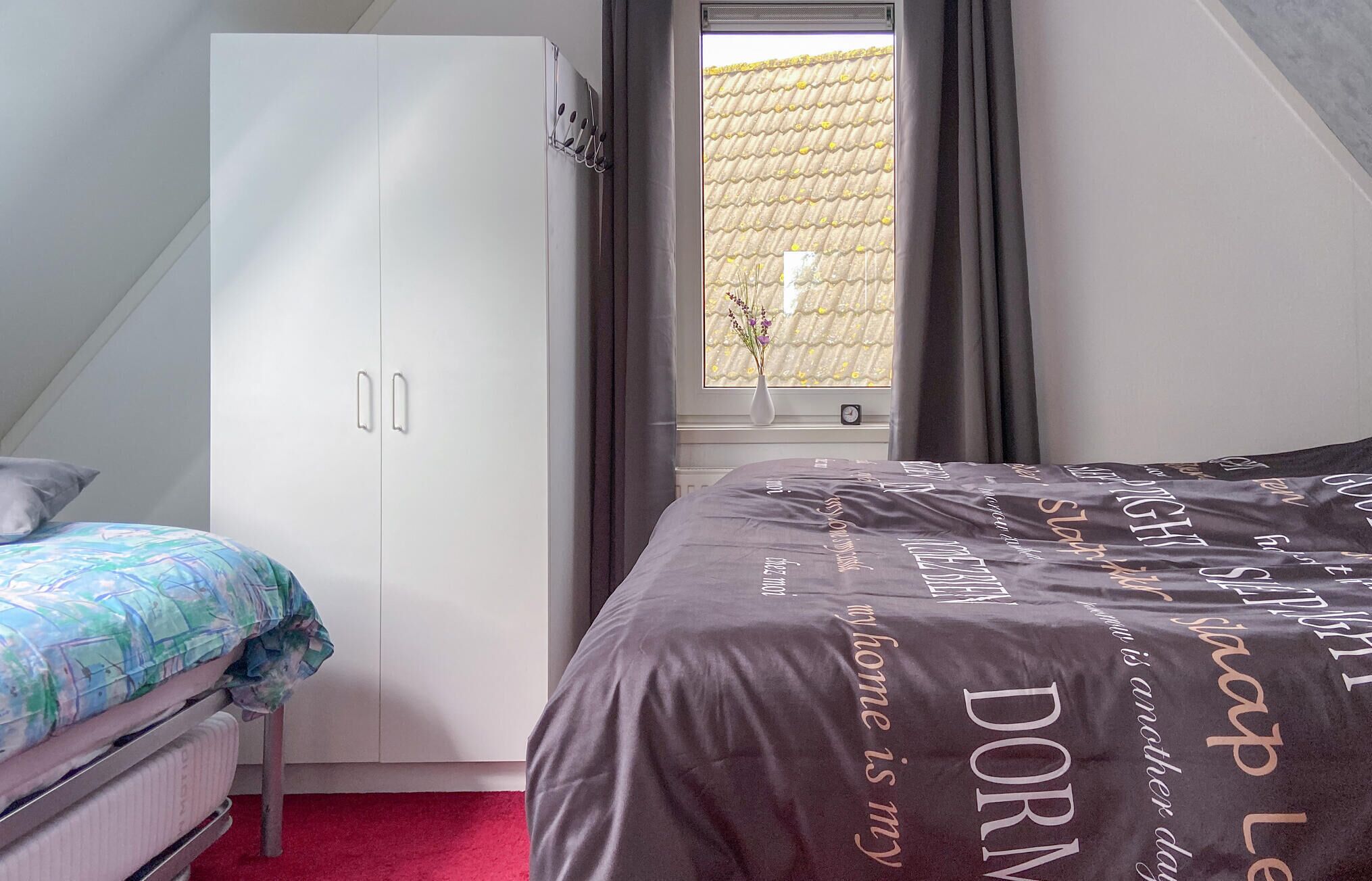 A bedroom with a bed, a wardrobe, a window with curtains, and a radiator.