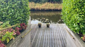 A wooden dock leading to a calm river with lush greenery on both sides. - Pet friendly home in Opperdoes (Opperdoes)