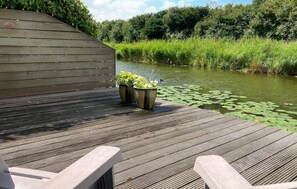 A wooden deck with two planters and a view of a river with lily pads.