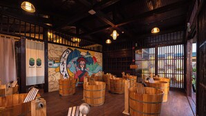A restaurant interior with wooden barrels as seating, a mural with a mountain and a character, and a view through a window. - Olala Glamping (Bao Lam 1)