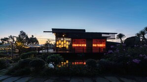 A modern building with a flat roof, large windows, and a reflective water feature in front. - Olala Glamping (Bao Lam 1)