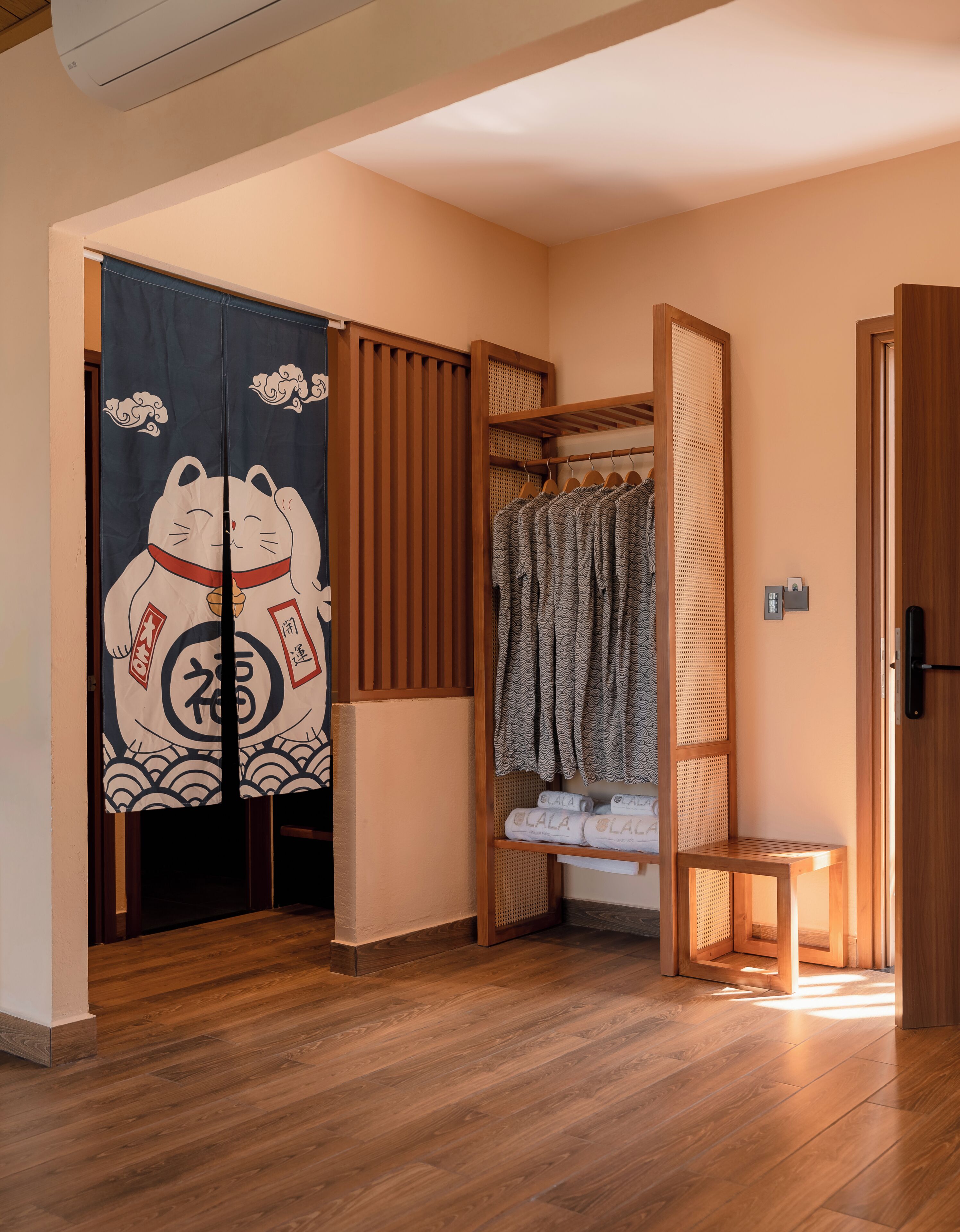 A room with a wooden floor, a sliding door with a cat design, a wooden wardrobe, and a small wooden bench.