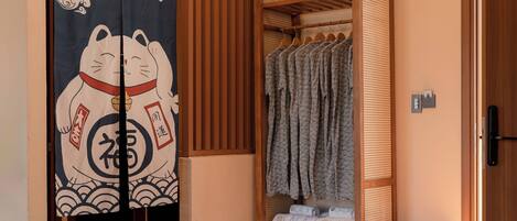 A room with a wooden floor, a sliding door with a cat design, a wooden wardrobe, and a small wooden bench.