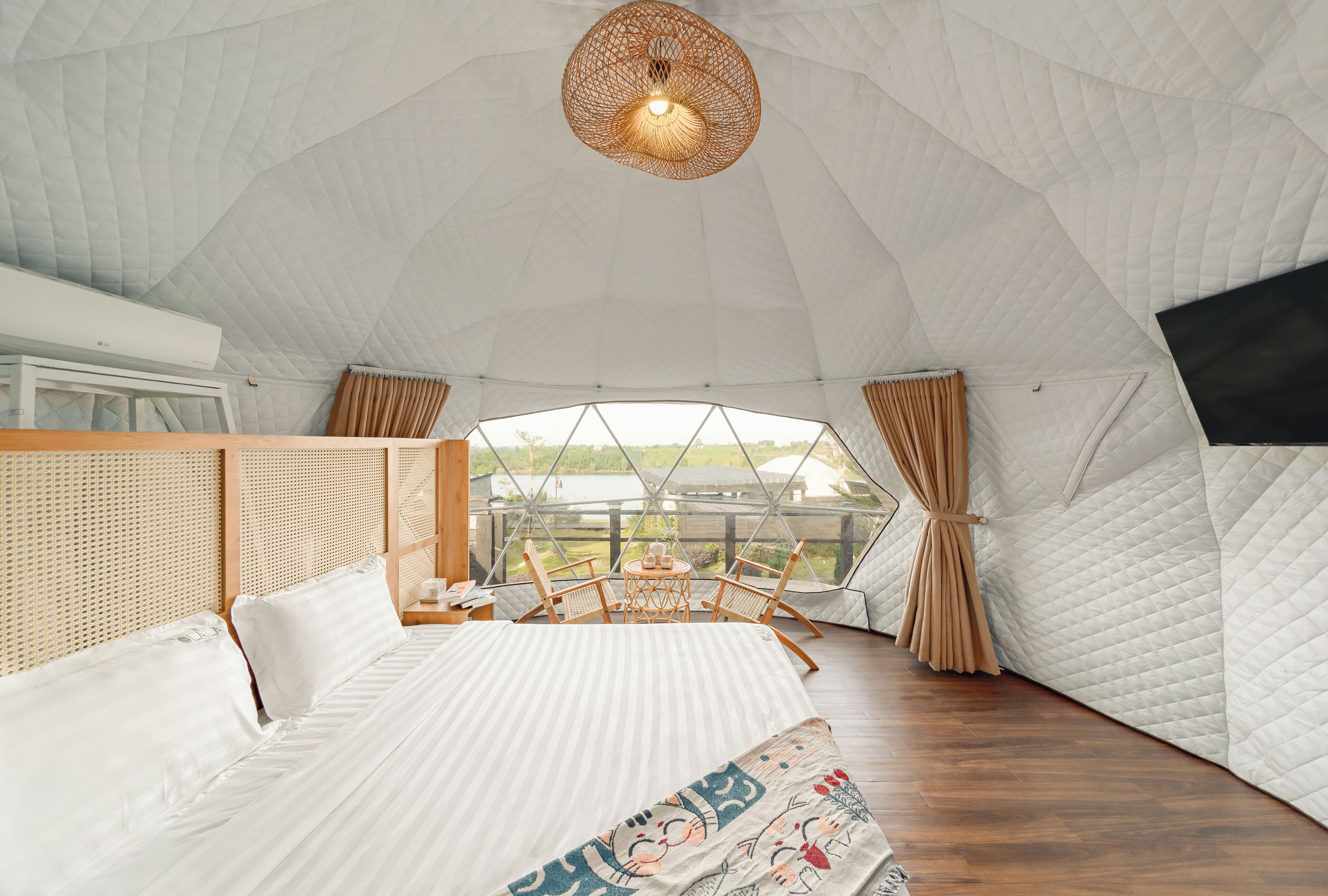A tent-style room with a bed, a table with chairs, and a view of the outdoors.