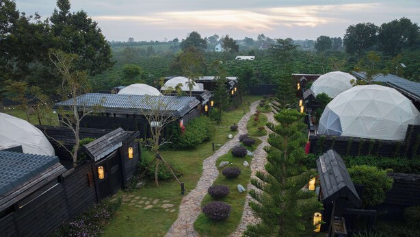 A series of dome-shaped cabins with stone pathways and greenery, surrounded by a forested landscape. - Olala Glamping (Bao Lam 1)