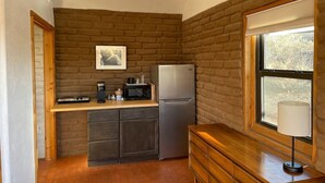 Una cocina compacta con refrigerador, microondas, cafetera y un gabinete de madera.