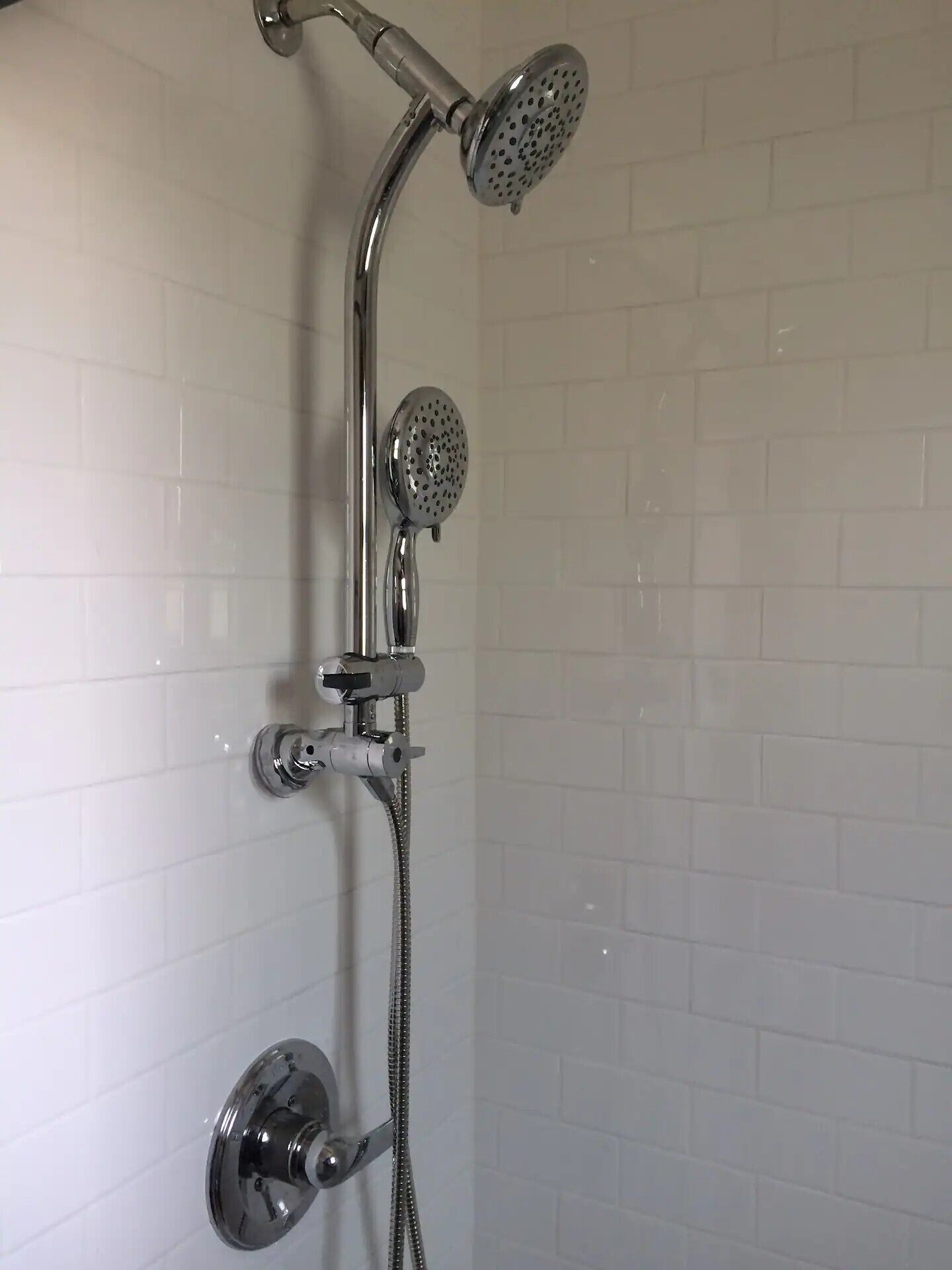 A shower with a handheld showerhead and a fixed showerhead.