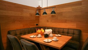 A dining area with a wooden table and cushioned booths, equipped with overhead lighting.