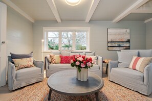 A cozy living room with two sofas, a coffee table, and a vase of flowers.