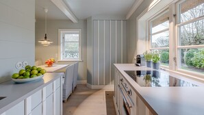 Una cocina moderna con una isla central, horno empotrado y ventana con vistas a un jardín.