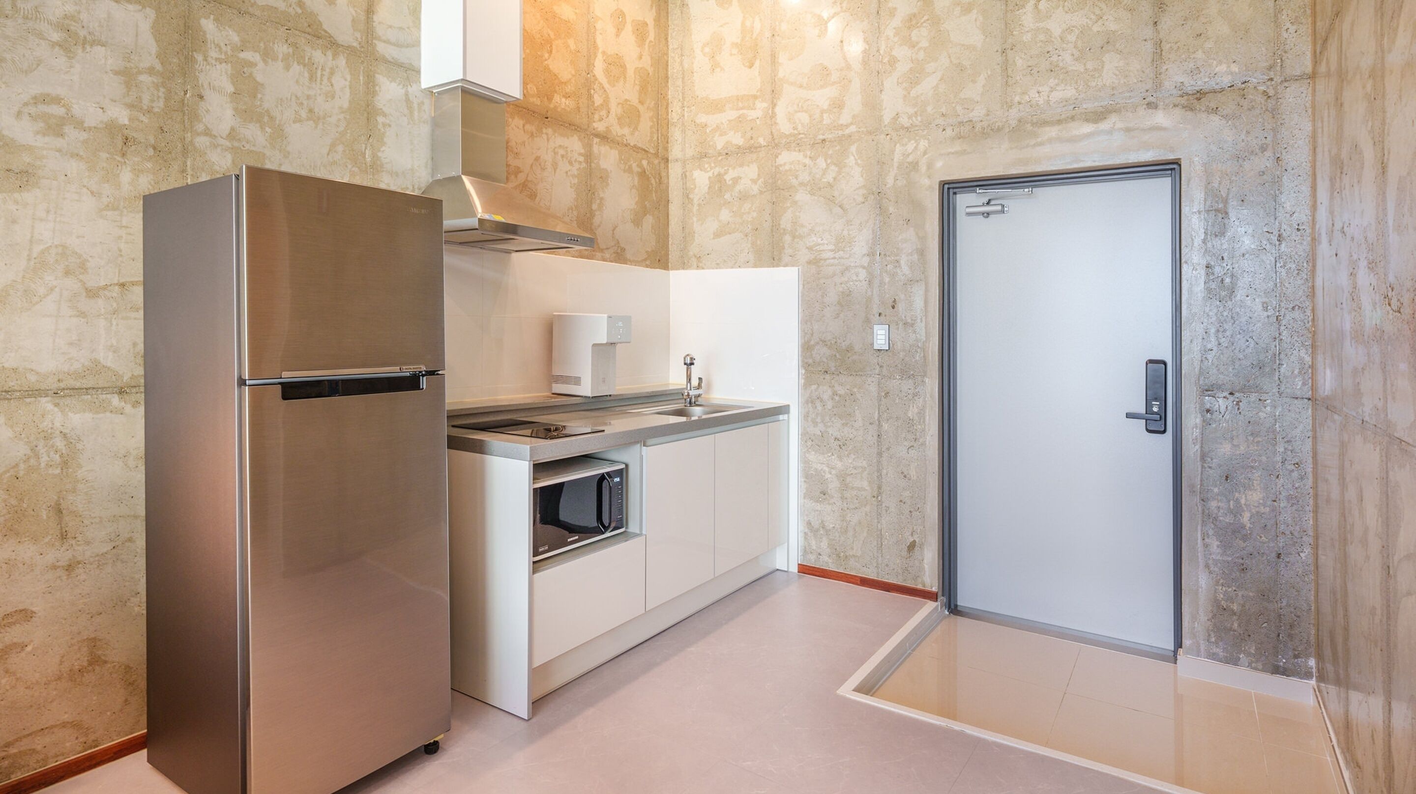 A compact kitchen with a built-in refrigerator, microwave, and stove, and a door leading to another room.
