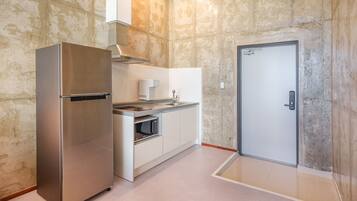 A compact kitchen with a built-in refrigerator, microwave, and stove, and a door leading to another room.