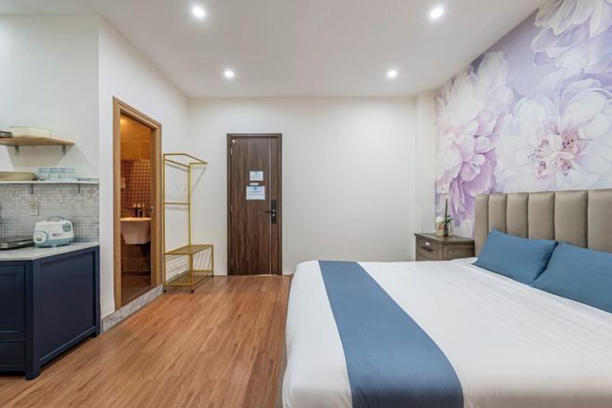 A bedroom with a bed, a nightstand, a dresser, and a door leading to a bathroom.