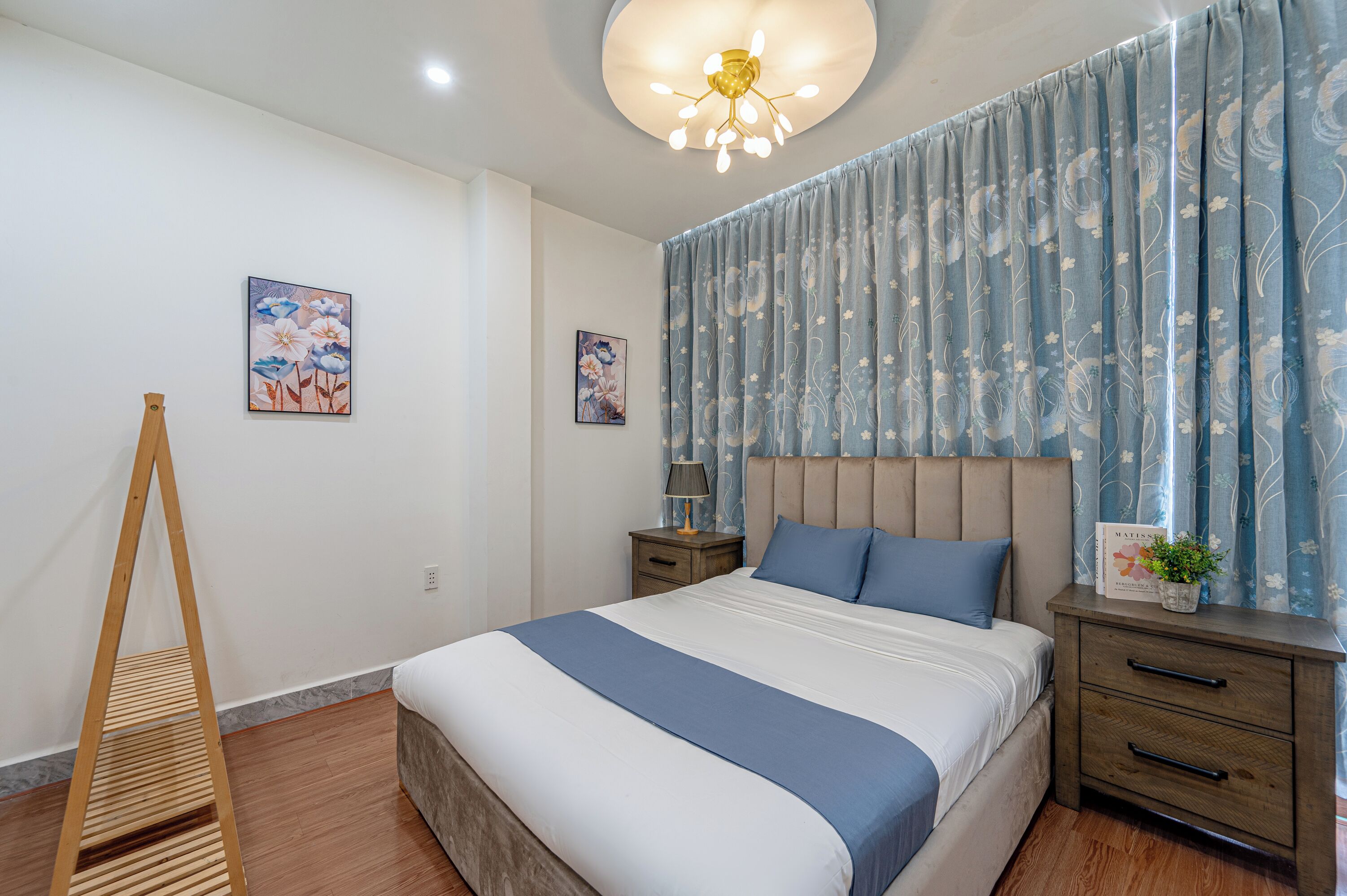 Un dormitorio con cama, mesitas de noche, una lámpara y un aplique de techo.