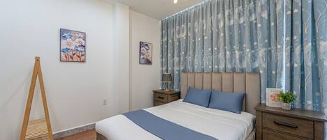 Un dormitorio con cama, mesitas de noche, una lámpara y un aplique de techo.