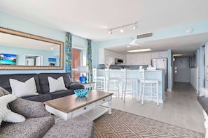 A compact living space with a sofa, coffee table, and a kitchenette area.