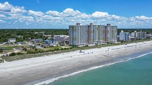 A beachfront hotel with multiple high-rise buildings, a sandy beach, and a clear blue sky. - Bay Watch 509 (North Myrtle Beach)