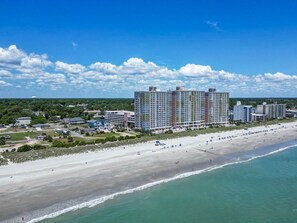 A beachfront hotel with multiple high-rise buildings, a sandy beach, and a clear blue sky. - Bay Watch 509 (North Myrtle Beach)