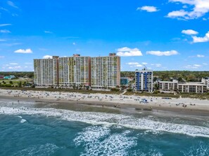 A beachfront hotel with multiple high-rise buildings, a sandy beach, and ocean waves.