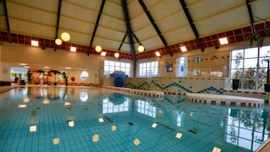 An indoor swimming pool with tiled walls and a high ceiling.