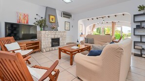 Een woonkamer met een televisie, open haard, bank en salontafel.
