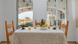 Een eethoek met een tafel gedekt voor twee personen, een fruitschaal en twee glazen jus d'orange.
