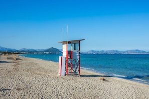 A lifeguard tower on a beach with clear skies and mountains in the background.