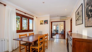 Un comedor con una mesa y sillas de madera, una ventana con cortinas, y una zona de cocina con mostrador y armarios.