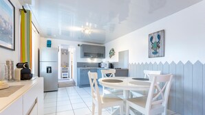 A modern kitchen with white cabinets, a dining table with chairs, and a microwave.