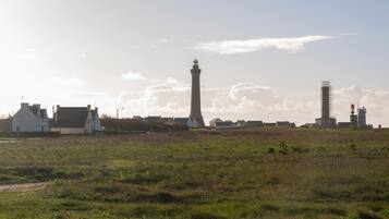 Un paisaje costero con un faro destacado, un edificio blanco y una obra en construcción.