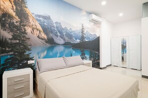 Un dormitorio con un mural de paisaje montañoso, una cama, una mesita de noche y un armario.
