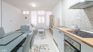 Une cuisine moderne avec une table à manger en verre, un four encastré et un dosseret carrelé.