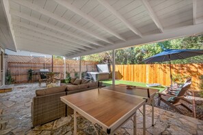 An outdoor patio with a ping pong table, wicker furniture, and a barbecue area. - Oaks Retro Cottage, Jacuzzi, Bistro Patio, Walk to Everything! (Thousand Oaks)