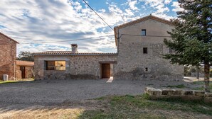 A stone building with a tiled roof, a gravel driveway, and a tree in the foreground. - Rural Home 'Cal Trumfet' with Mountain View, Private Terrace and Wi-Fi (Casserres)