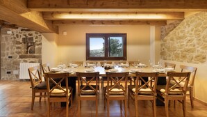 A dining area with a stone wall, wooden ceiling beams, and a view through a window. - Rural Home 'Cal Trumfet' with Mountain View, Private Terrace and Wi-Fi (Casserres)