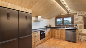 A modern kitchen with wooden cabinets, stainless steel appliances, and a stone wall. - Rural Home 'Cal Trumfet' with Mountain View, Private Terrace and Wi-Fi (Casserres)