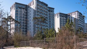 A high-rise building with multiple balconies, a sandy beach area in the foreground, and some trees. - Mistral Porta Mare by Interhome (Dziwnówek)