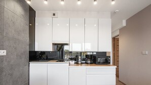 A modern kitchen with white cabinets, a black coffee maker, and a microwave. - Mistral Porta Mare by Interhome (Dziwnówek)