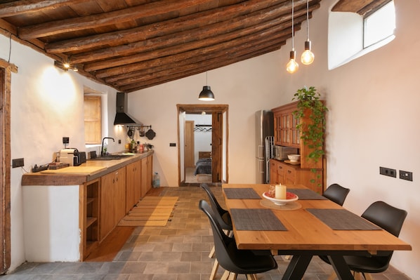 A kitchen with wooden cabinets, a dining table with chairs, and a hanging light fixture.