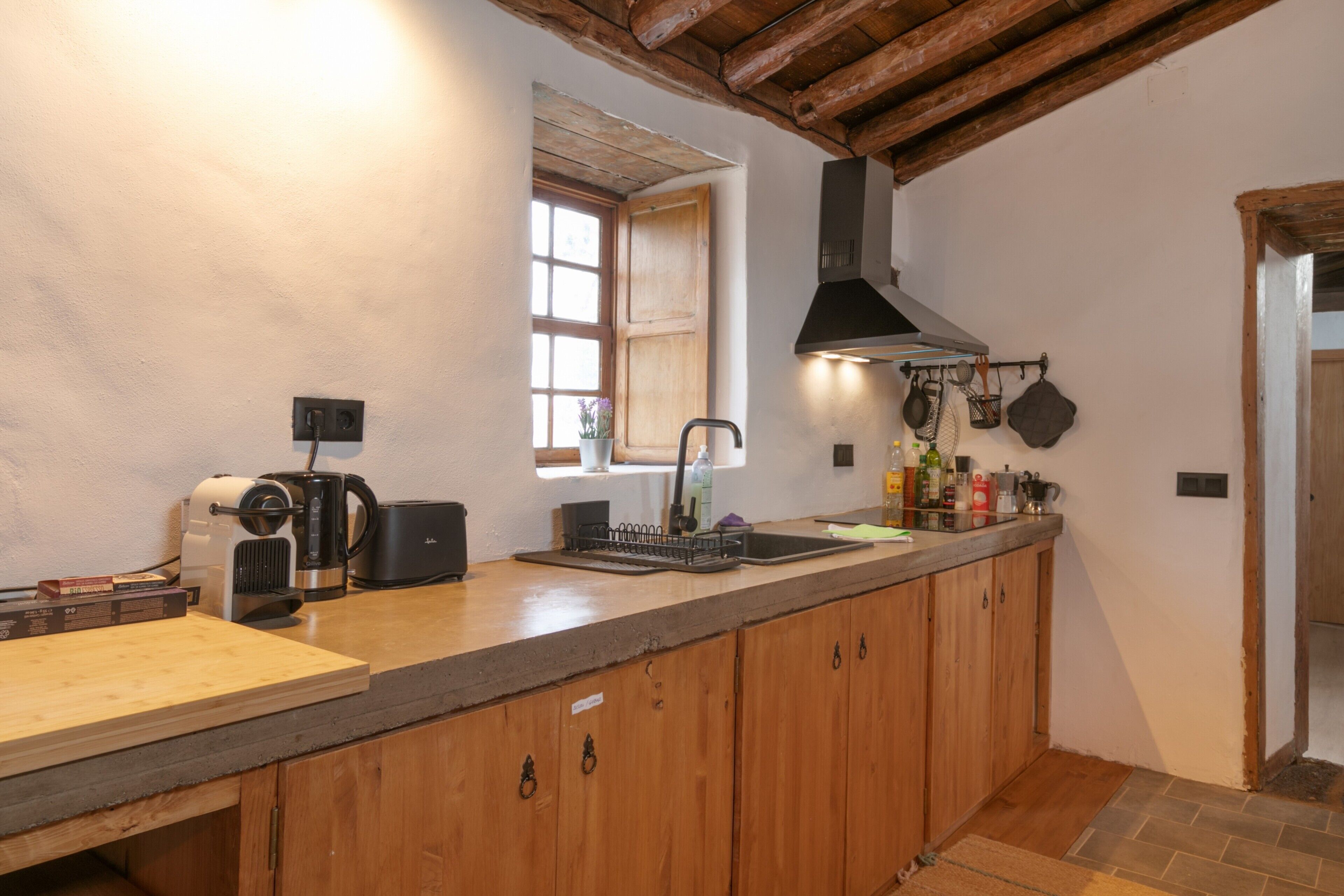 Une cuisine avec des meubles en bois, une machine à café, un évier et une fenêtre donnant sur un beau paysage.