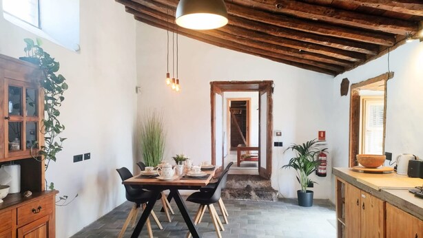 Un comedor rústico con una mesa de madera, sillas y una lámpara colgante.