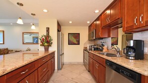 Una cucina moderna con piani in granito, elettrodomestici in acciaio inossidabile, mobili in legno e illuminazione a sospensione.