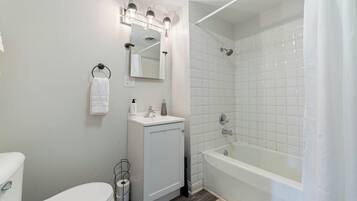 Un baño con inodoro, lavamanos, espejo y bañera.