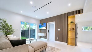 Una sala de estar moderna con un sofá beige, una mesita de centro y un ventanal con vistas a un jardín.
